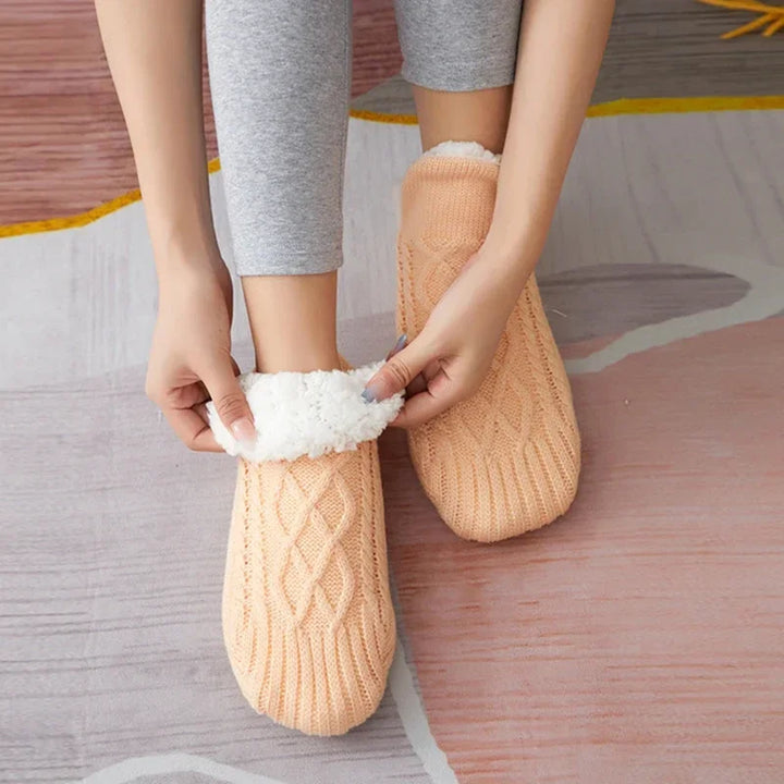 Getragene apricotfarbene Thermosocken mit einer Hand, die das weiße Futter zeigt.