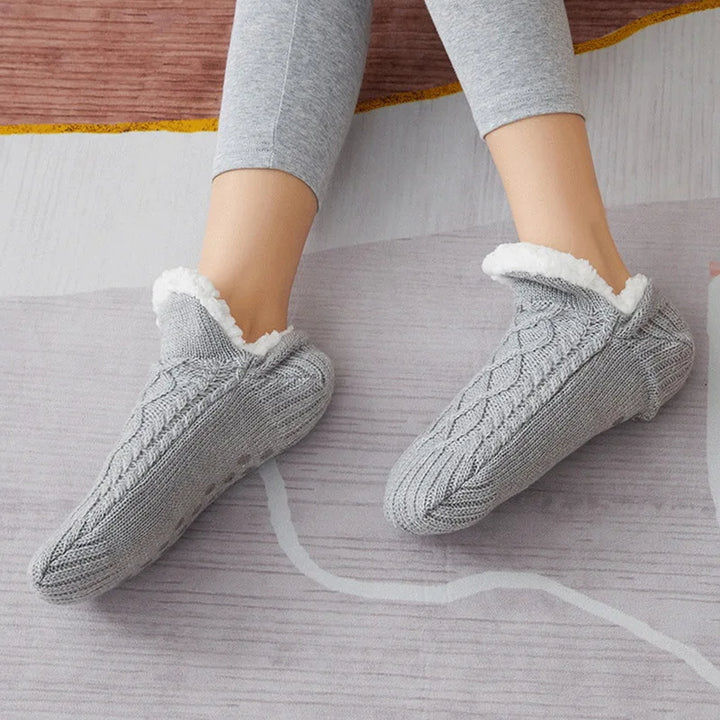 Getragene graue Thermosocken nebeneinander auf einem Teppich.