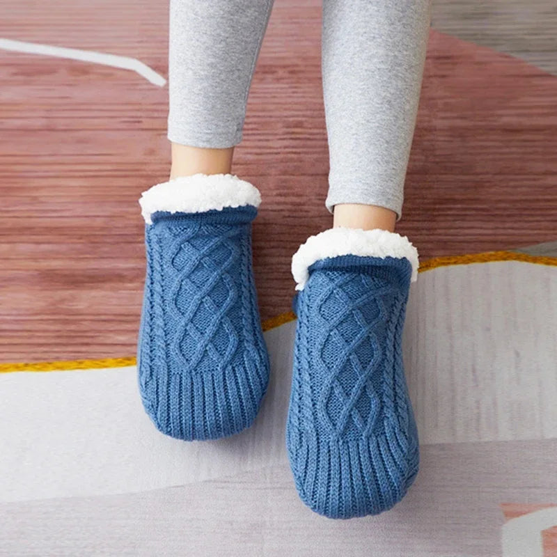 Getragenes Paar blauer Thermosocken mit Zopfmuster.