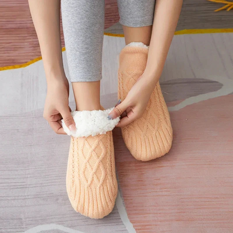 Getragene apricotfarbene Thermosocken mit einer Hand am weißen Rand.