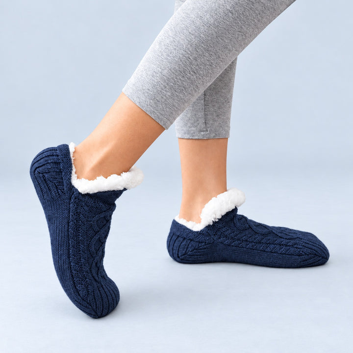 Marineblaue Thermosocken in seitlicher Trageansicht, ein Fuß flach und einer auf der Zehenspitze, vor hellblaugrauem Hintergrund.