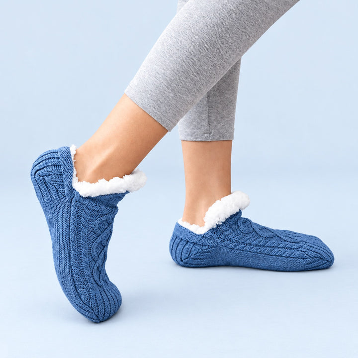 Blaue Thermosocken in seitlicher Trageansicht, ein Fuß flach und einer auf der Zehenspitze, vor hellblauem Hintergrund.