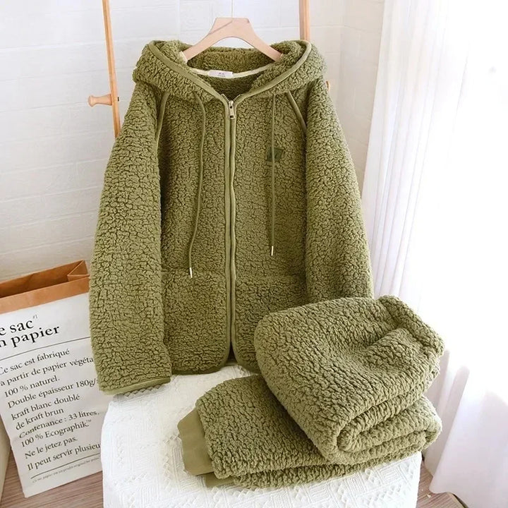 Ansicht des olivgrünen Modells: Pyjamajacke mit Kapuze und Reißverschluss am Bügel und gefaltete Hose.