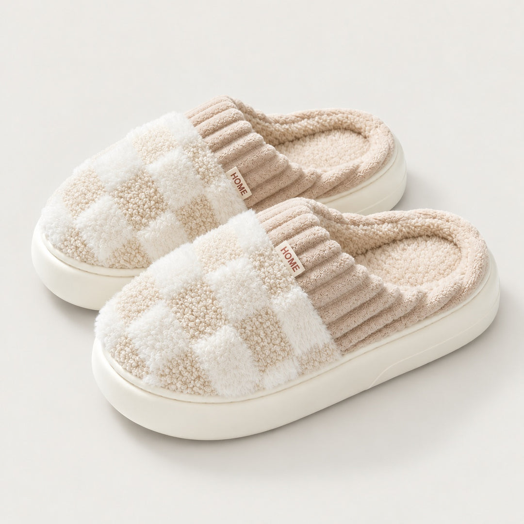 Paar Partner-Hausschuhe mit Schachbrettmuster in Beige auf graugebrochenem cremeweißem Hintergrund.