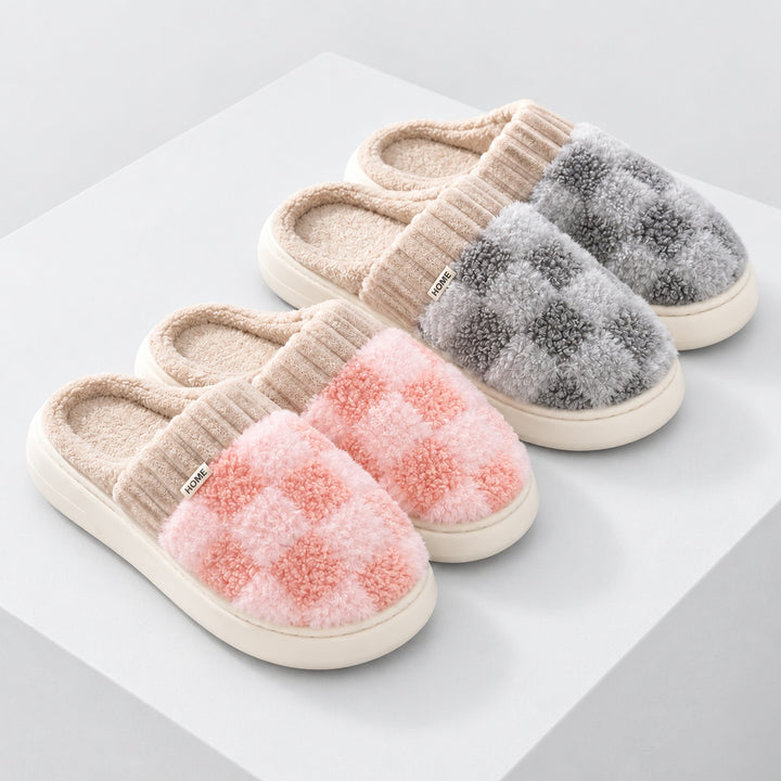 Zwei Paar Partner-Hausschuhe mit rosa und grauem Schachbrettmuster auf einem sehr hellgrauen Podest.