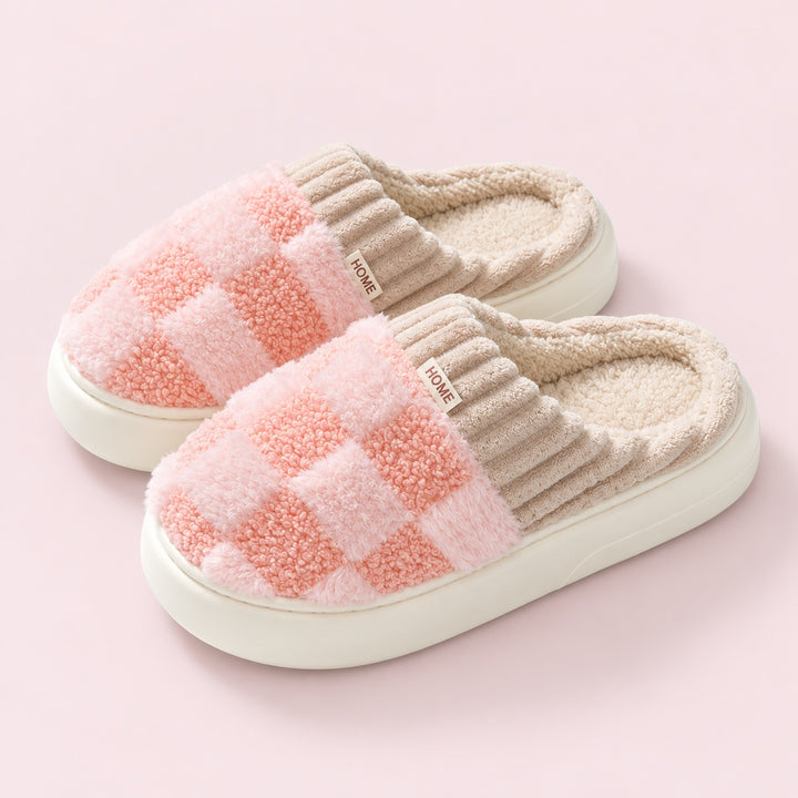 Paar Partner-Hausschuhe mit Schachbrettmuster in Rosa auf puderrosafarbenem Hintergrund.