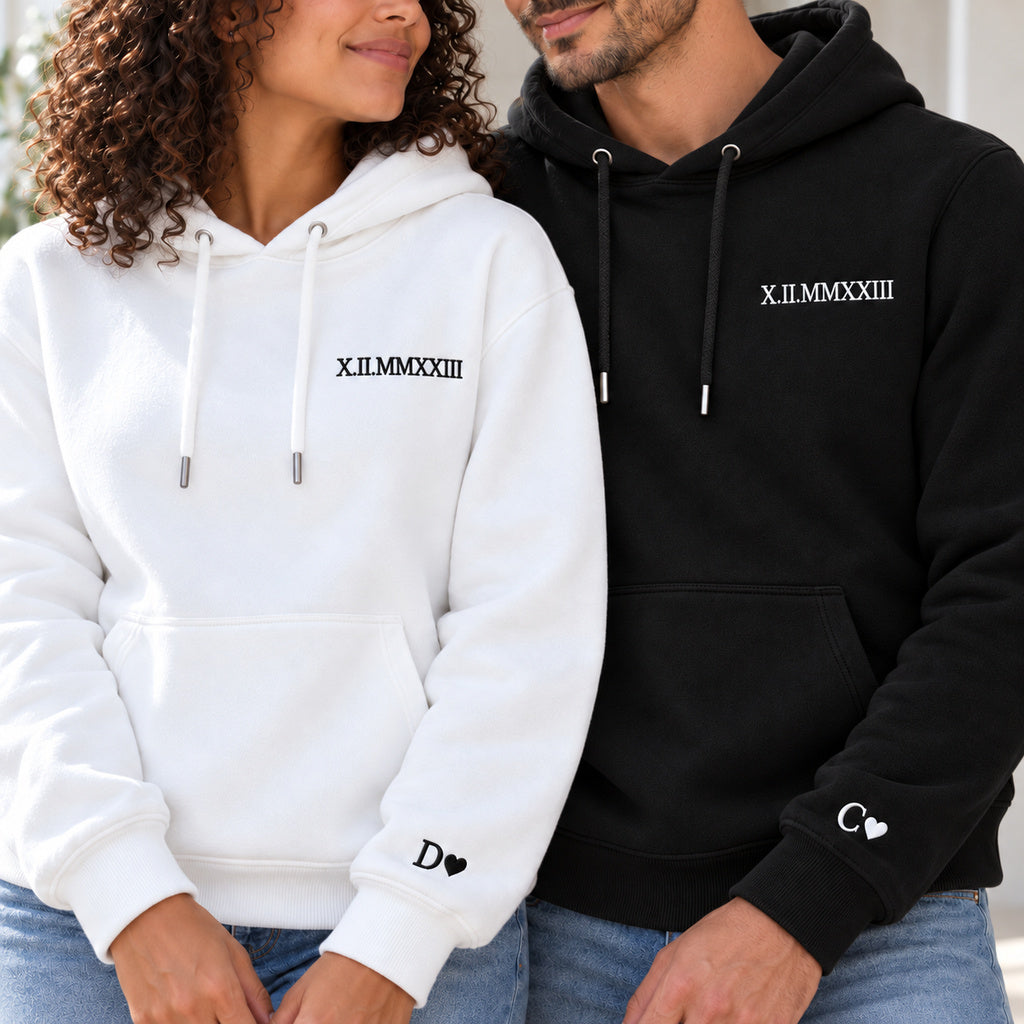 Vue rapprochée des sweats couple : broderies noires sur blanc et blanches sur noir, date à la poitrine et initiales D et C aux poignets.
