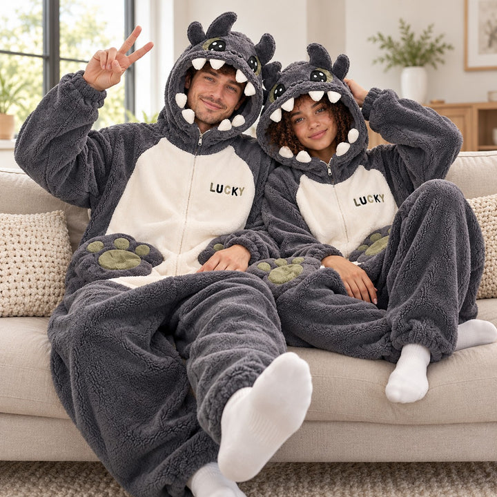 Pyjama Chaud Couple porté par un couple assis sur un canapé clair, capuches monstre et détails pattes sur les genoux