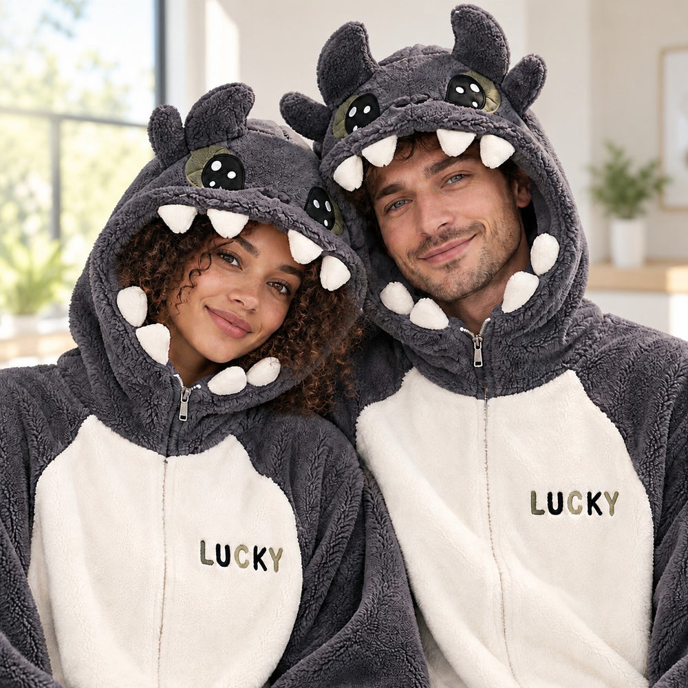 Warmer Partnerpyjama in Grau und Creme, von einem Paar in einem hellen Wohnraum getragen, Monsterkapuzen mit Zähnen