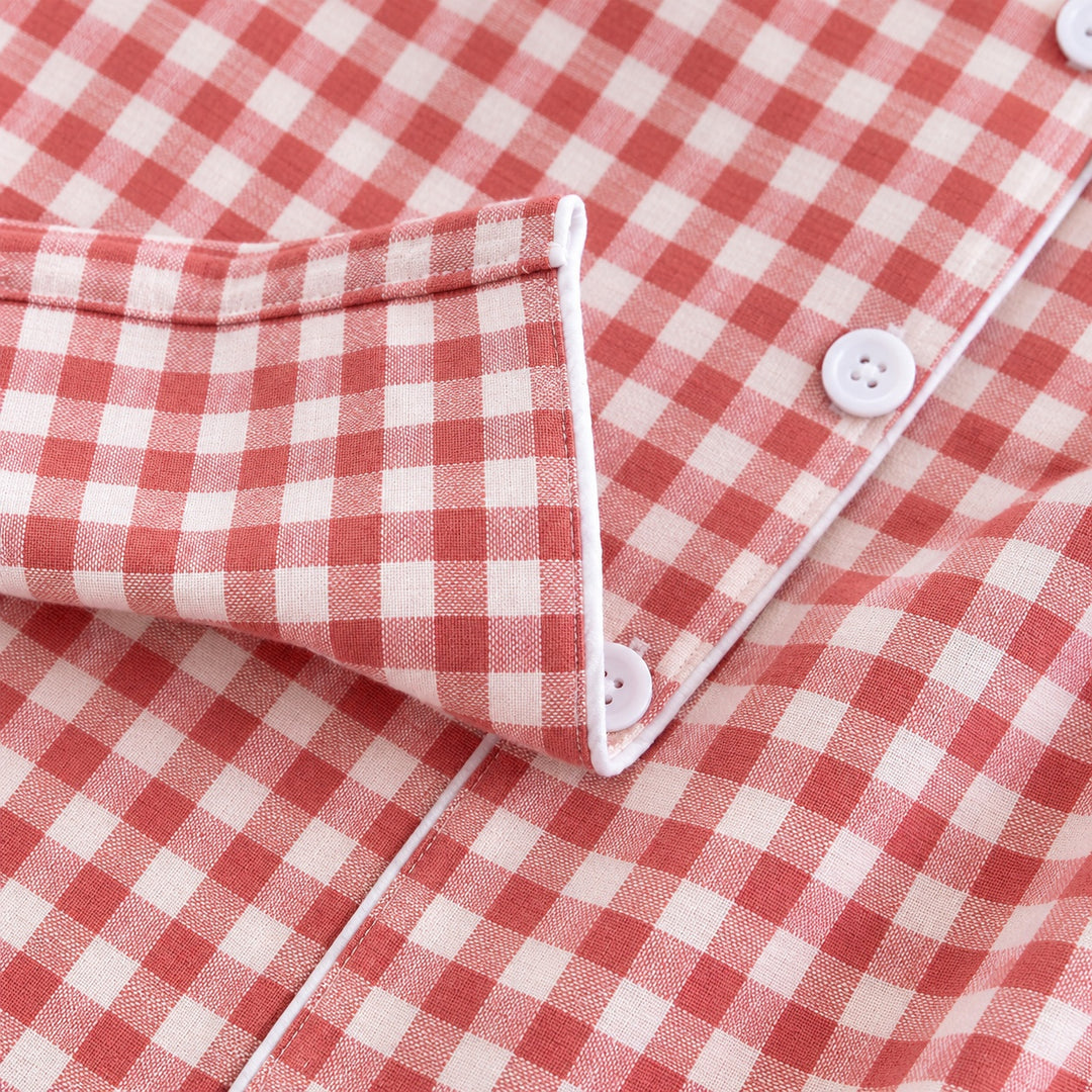 Gros plan du poignet et des boutons blancs du pyjama à carreaux corail.