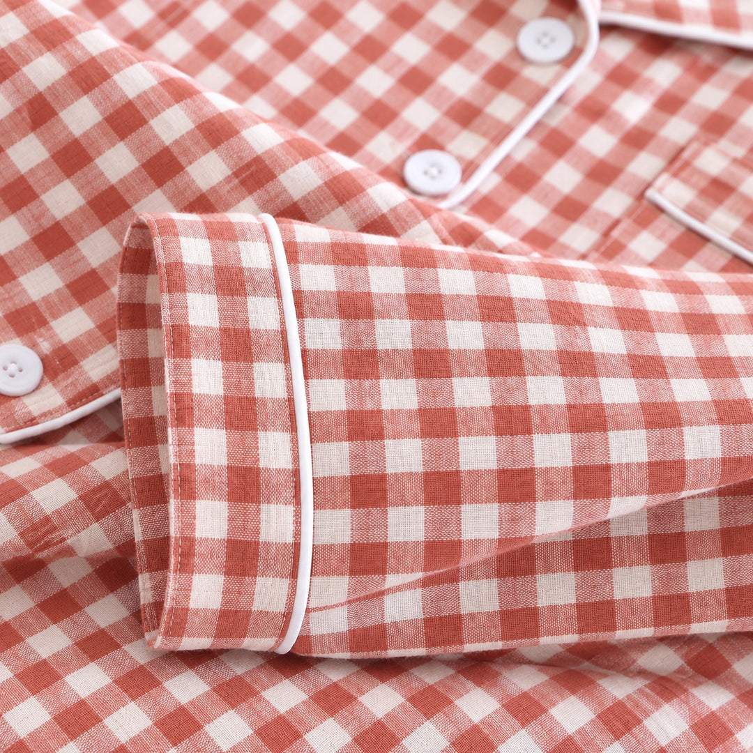 Détail du poignet à passepoil blanc du pyjama à carreaux corail.