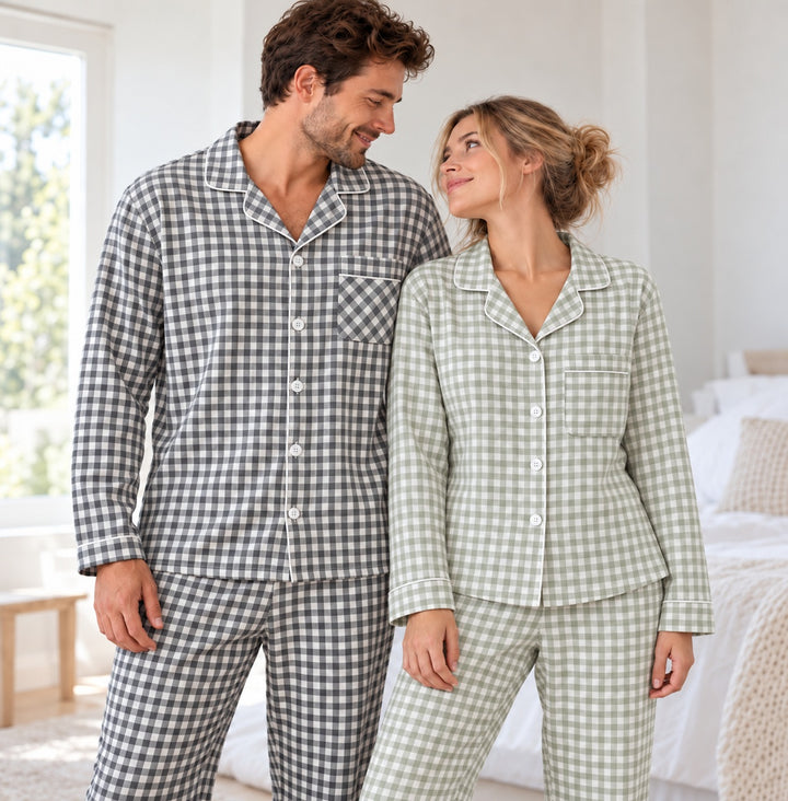 Couple portant les pyjamas à carreaux vert sauge et gris, cadré de la tête aux cuisses dans une chambre lumineuse.