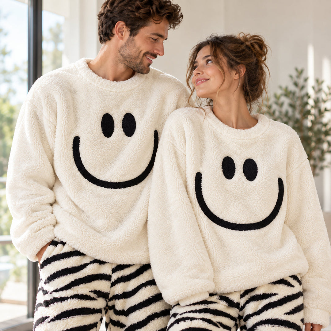 Paar im passenden weißen Plüschpyjama mit Smiley-Oberteil und schwarz-weiß gestreifter Hose