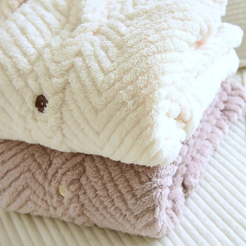 Gros plan du pyjama blanc plié, avec bouton foncé et texture en chevrons.
