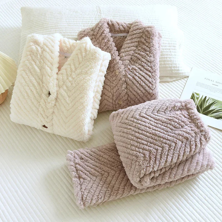 Pyjamas blanc et violet pliés, montrant les cols châles, les boutons et le relief en chevrons.