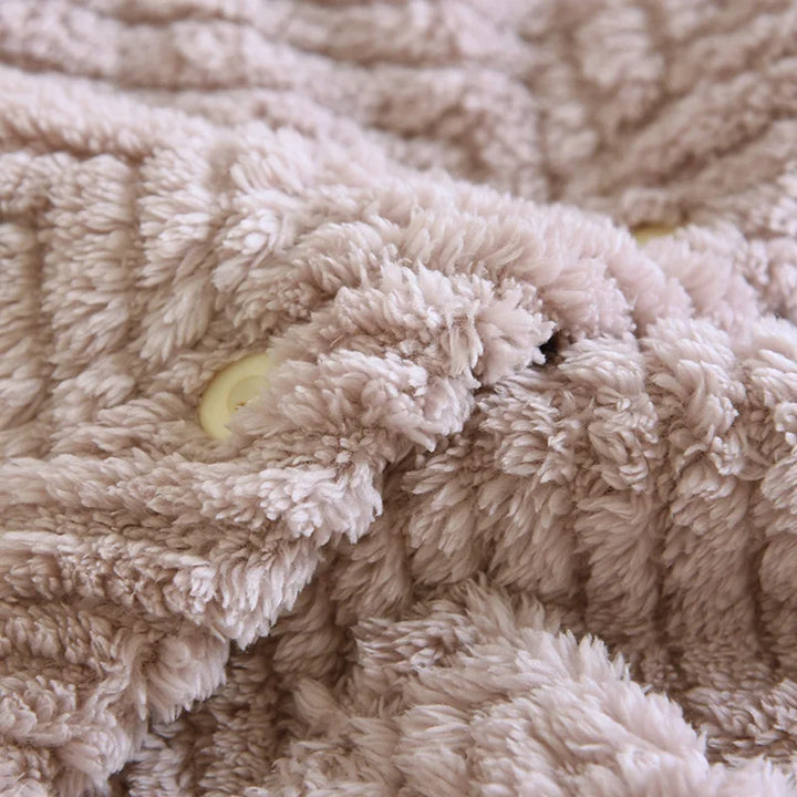 Gros plan d’un bouton clair et du tissu à chevrons du pyjama violet.