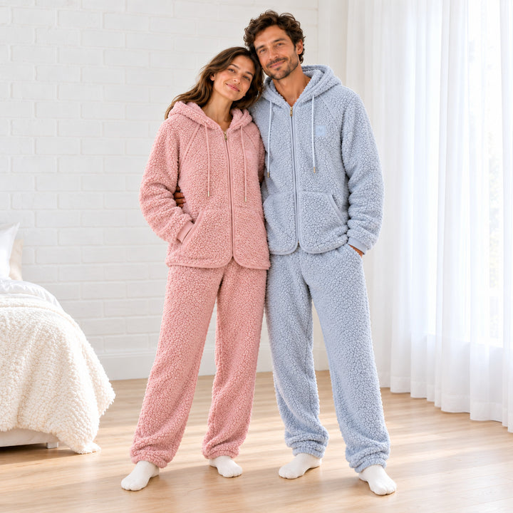 Paar in flauschigen Pyjamas in Altrosa und Graublau mit Kapuzenjacken und passenden Hosen, Ganzkörperansicht.