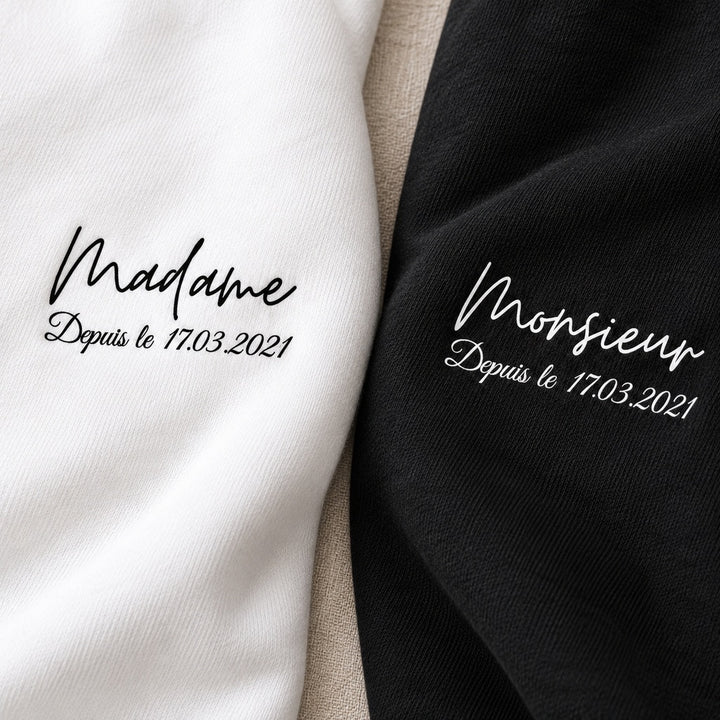 Gros plan des inscriptions Monsieur et Madame et de la date personnalisée imprimées sur les sweats noir et blanc.