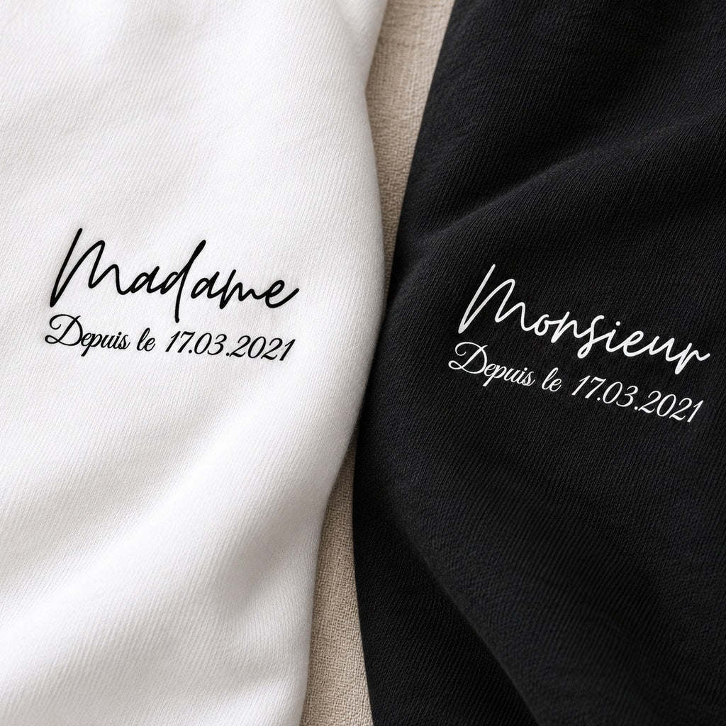 Gros plan des inscriptions Monsieur et Madame et de la date personnalisée imprimées sur les sweats noir et blanc.