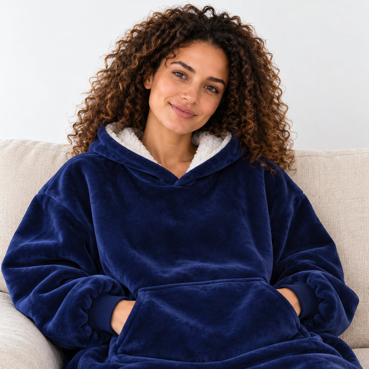 Femme portant le sweat plaid bleu marine, assise sur un canapé beige, cadrée du visage à la taille.
