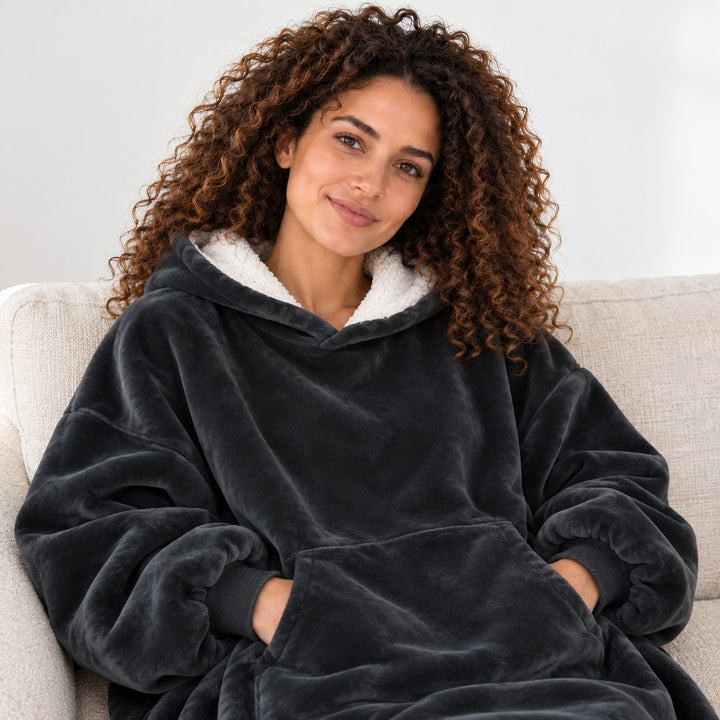 Femme portant le sweat plaid noir, assise sur un canapé beige, cadrée du visage à la taille.