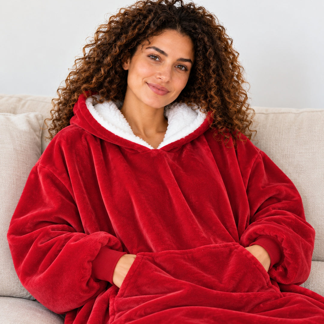 Femme portant le sweat plaid rouge, assise sur un canapé beige, cadrée du visage à la taille.